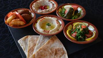 Une table garnie de divers plats, notamment du houmous, des falafels et des salades, accompagnée de pains plats.