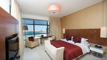 Una habitación de hotel moderna con una cama grande, un escritorio, una silla, un televisor y vistas a la ciudad.