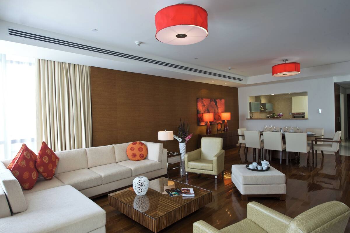 Un salón moderno de hotel con un sofá, sillones, una mesa de centro y un comedor.