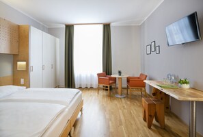 Relax in a comfortable double bed with a wooden frame, surrounded by a desk and chair for work and a small table with a chair for dining.
