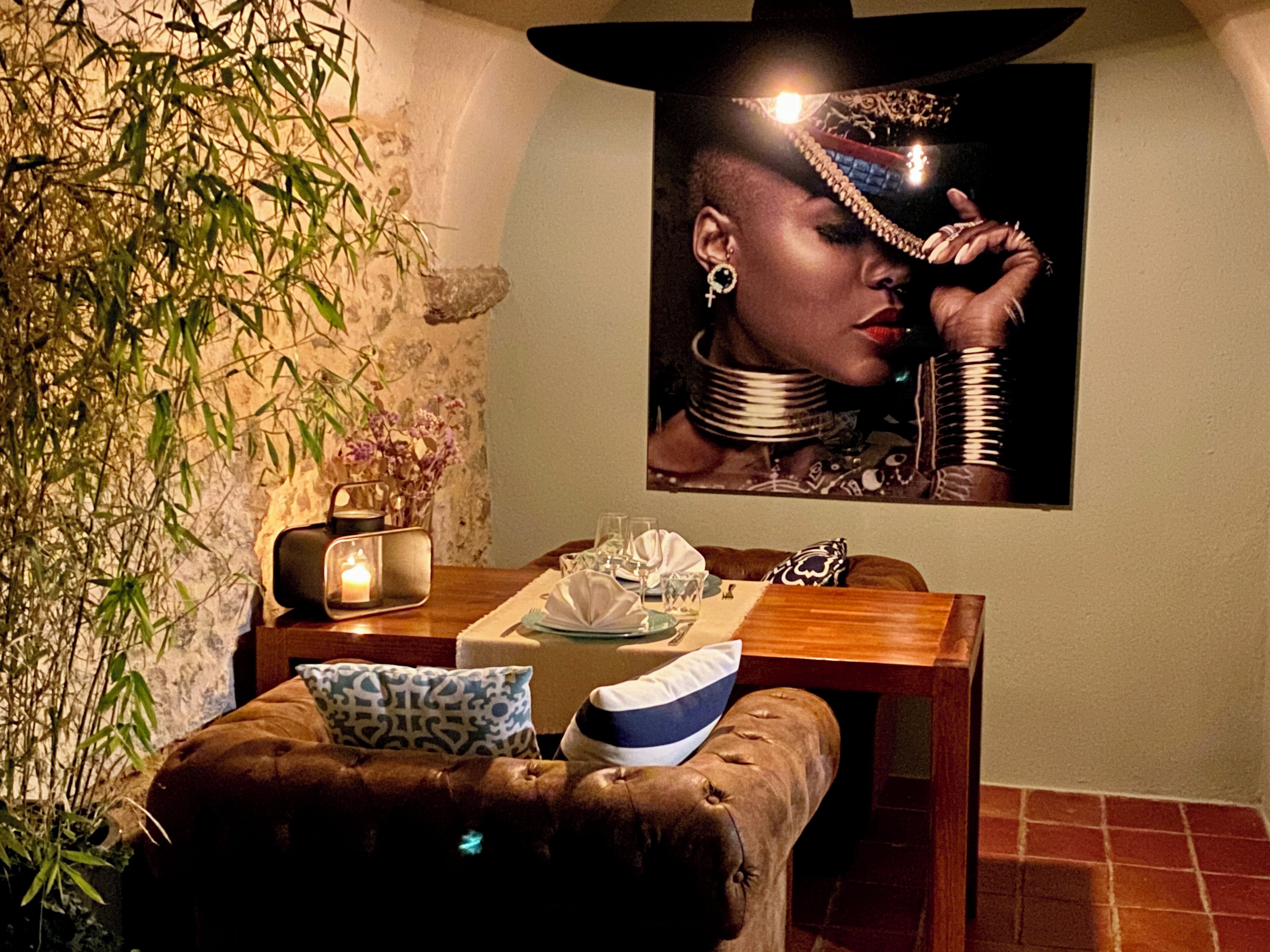 A dining area with a wooden table, a cushioned bench, a decorative mirror, and a wall-mounted painting.