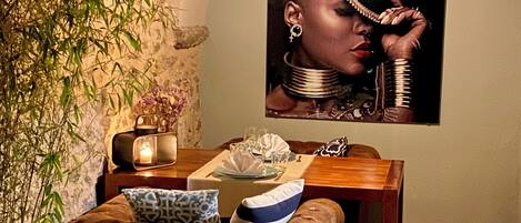 A dining area with a wooden table, a cushioned bench, a decorative mirror, and a wall-mounted painting.