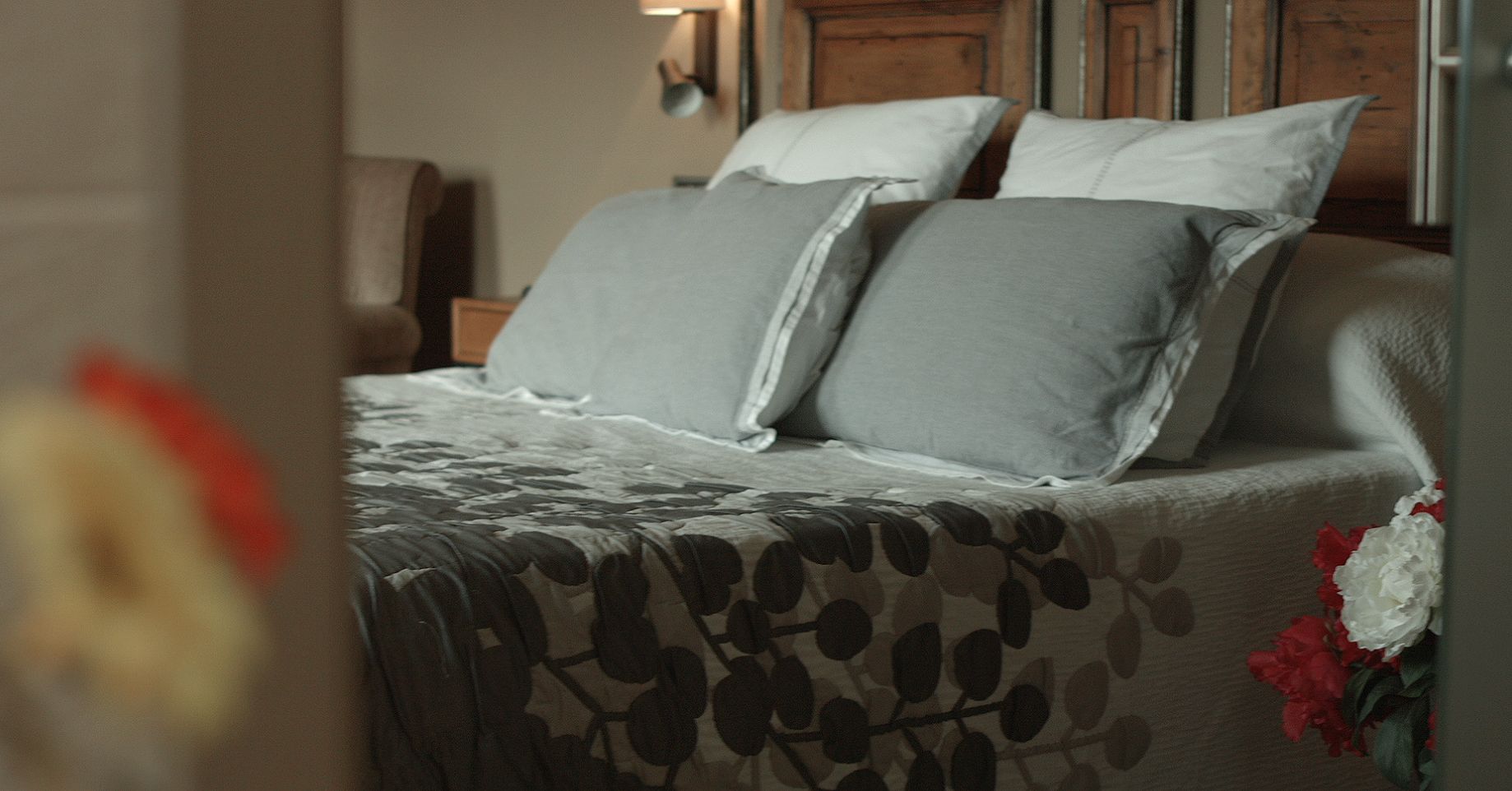 A bed with a patterned bedspread and two pillows.