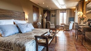 A hotel room with a large bed, a desk, two chairs, and a dining table. - HOTEL FINCA EL VENTÓS (Sant Aniol de Finestres)