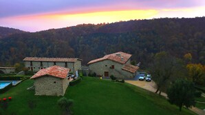 A stone building with a swimming pool and red chairs. - HOTEL FINCA EL VENTÓS (Sant Aniol de Finestres)