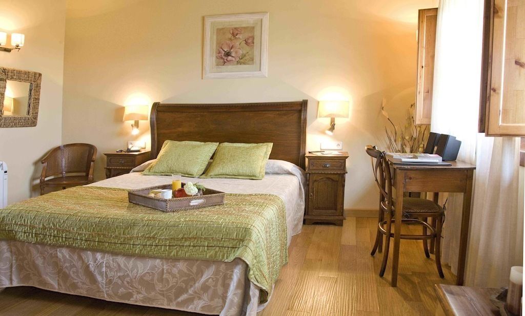 A hotel room with a large bed, two bedside tables, a desk with a chair, and a mirror on the wall.