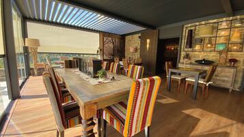 A spacious dining area with a long wooden table, striped chairs, and a stone wall backdrop.