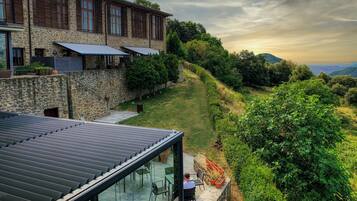 A stone building with a terrace, outdoor seating, and a view of the surrounding landscape.