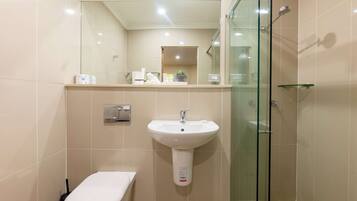 Une salle de bain moderne avec un lavabo blanc, des toilettes et une douche à parois de verre.