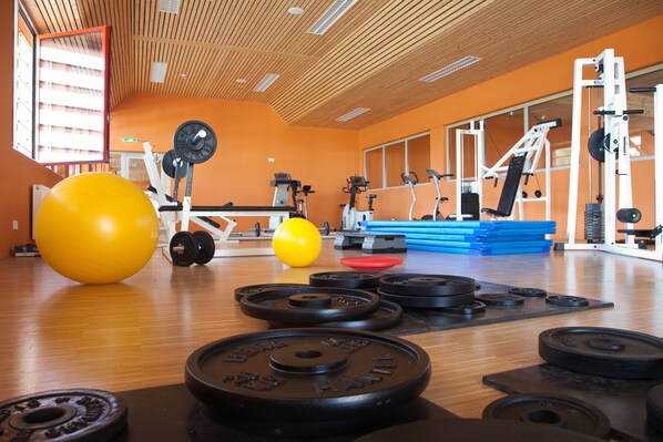 Un gimnasio con equipo de ejercicio, discos de pesas y pelotas de entrenamiento.