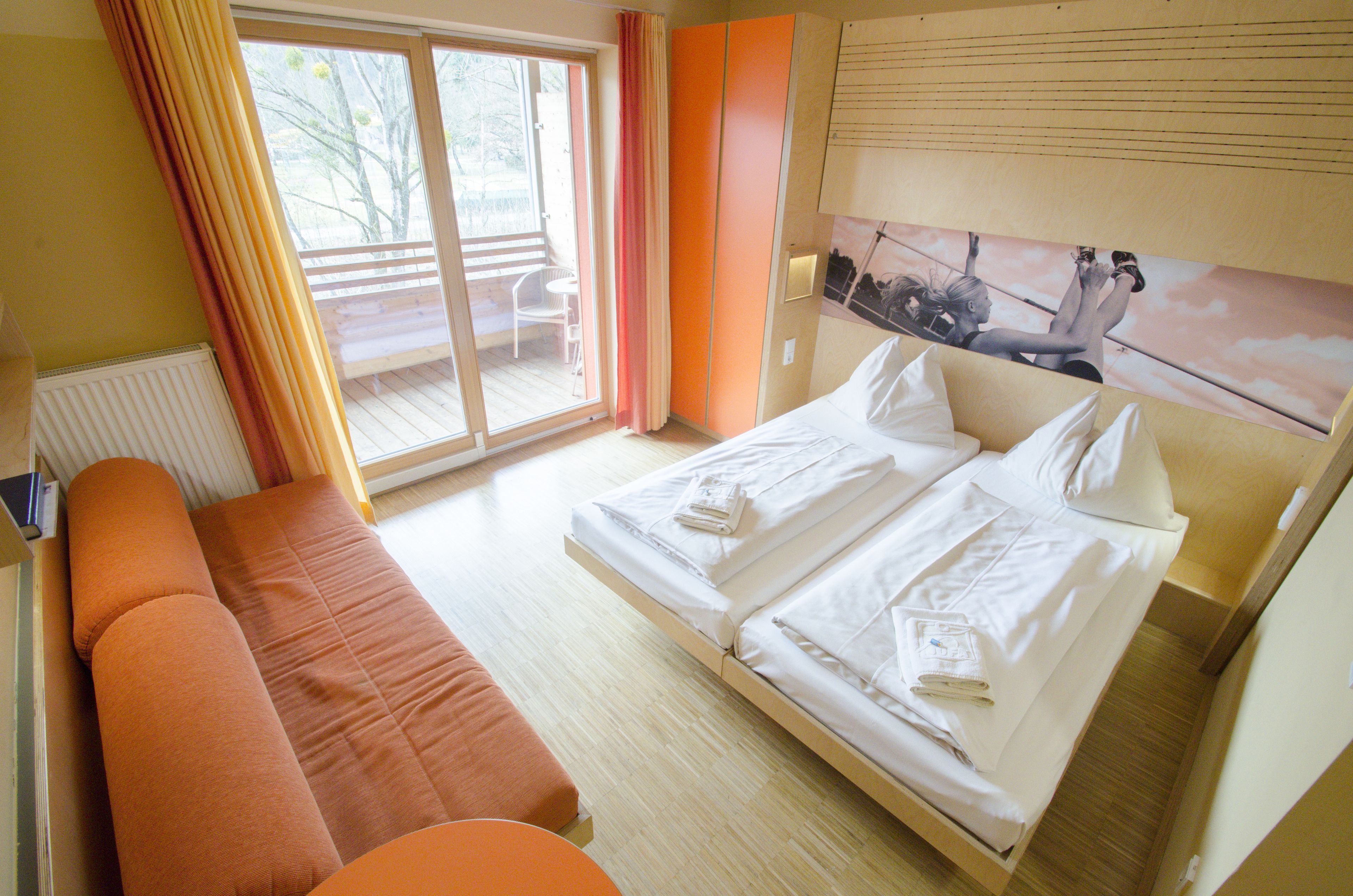 Habitación de hotel con cama, sofá, ventana con cortinas y vistas al exterior.