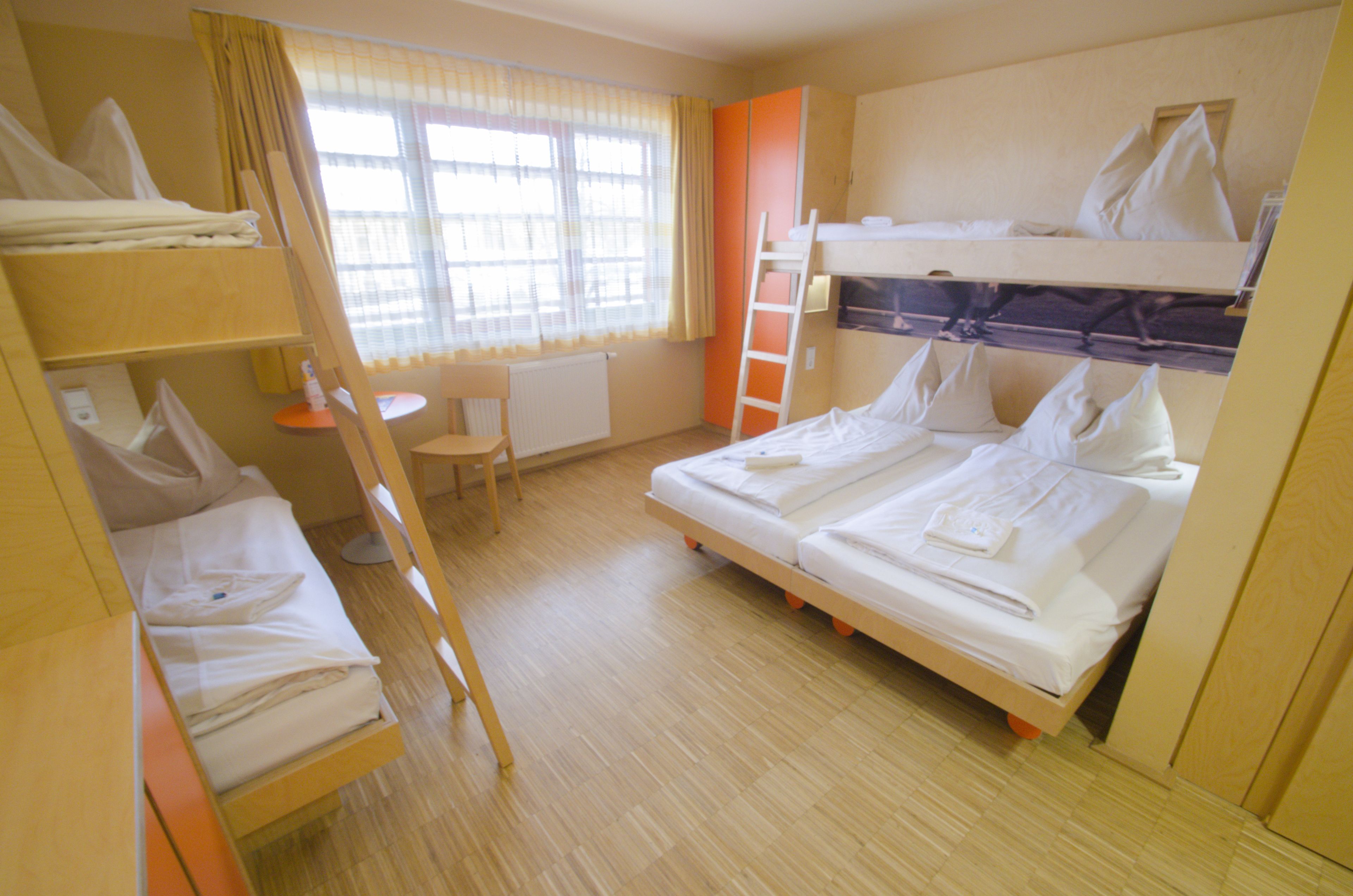 A room with bunk beds, a desk, and a chair.