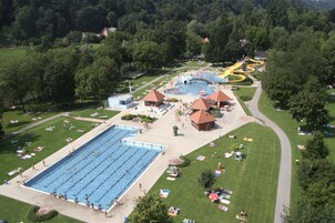 Vista aérea de um resort com uma piscina grande, um tobogã aquático e uma área gramada bem cuidada.