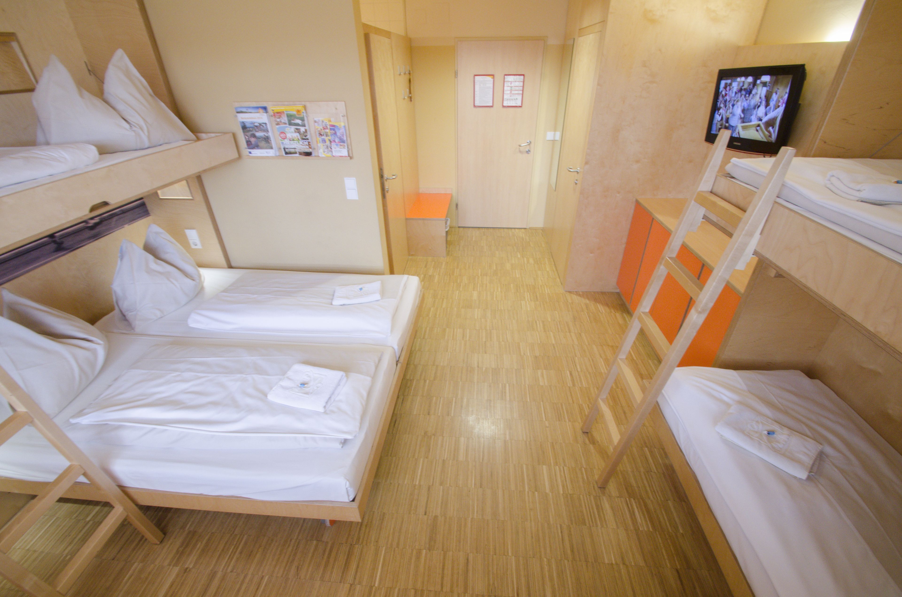 A hotel room with bunk beds, a television, and a small table.