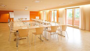 Una sala conferenze con un lungo tavolo, sedie, un proiettore e una lavagna.