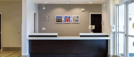 Un área de recepción con diseño moderno, que incluye un mostrador de recepción, una cámara de seguridad montada en la pared y cuadros enmarcados.