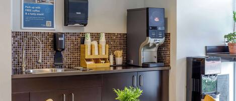 Une cuisine moderne équipée d’une machine à café, d’un évier et d’un crédence carrelée.