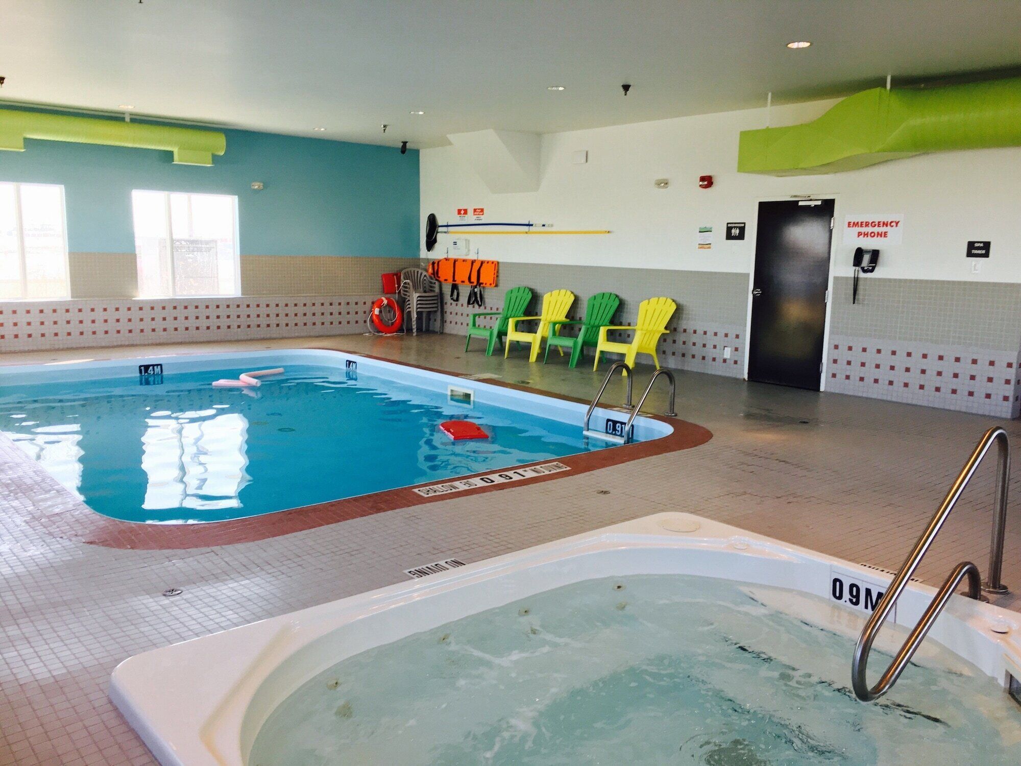 An indoor swimming pool with clear water, marked depth lines, and a lifeguard chair area.