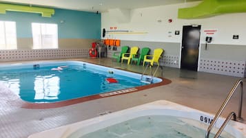 An indoor swimming pool with clear water, marked depth lines, and a lifeguard chair area.