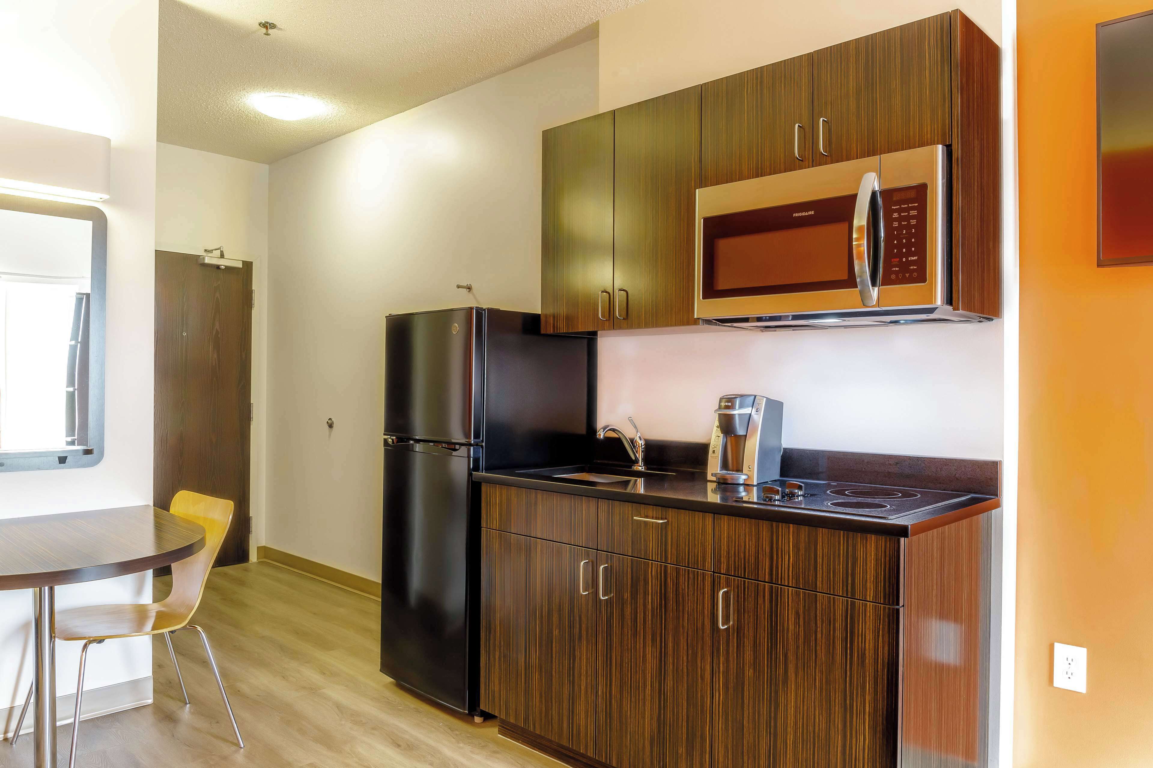 A compact kitchen with a refrigerator, microwave, and a coffee maker on the countertop.