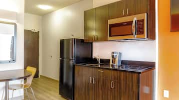 A compact kitchen with a refrigerator, microwave, and a coffee maker on the countertop.