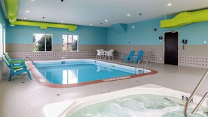 An indoor swimming pool with a hot tub, seating area, and a door leading to another room. - Motel 6 Headingley, MB - Winnipeg West (Headingley)