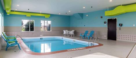 Una piscina interior con jacuzzi, zona de estar y una puerta que da a otra habitación.