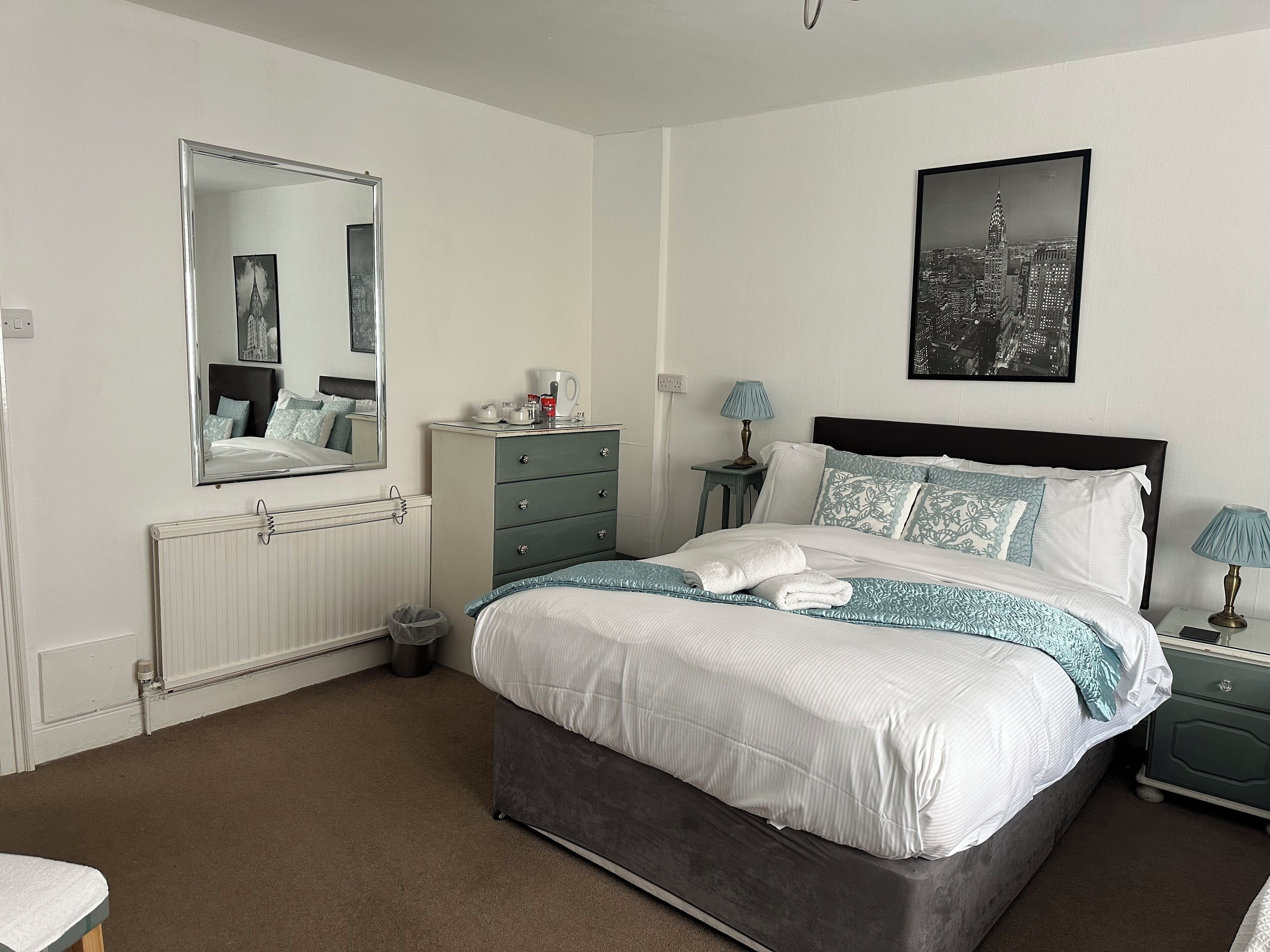 A neatly arranged bedroom with a bed, dresser, and bedside tables.