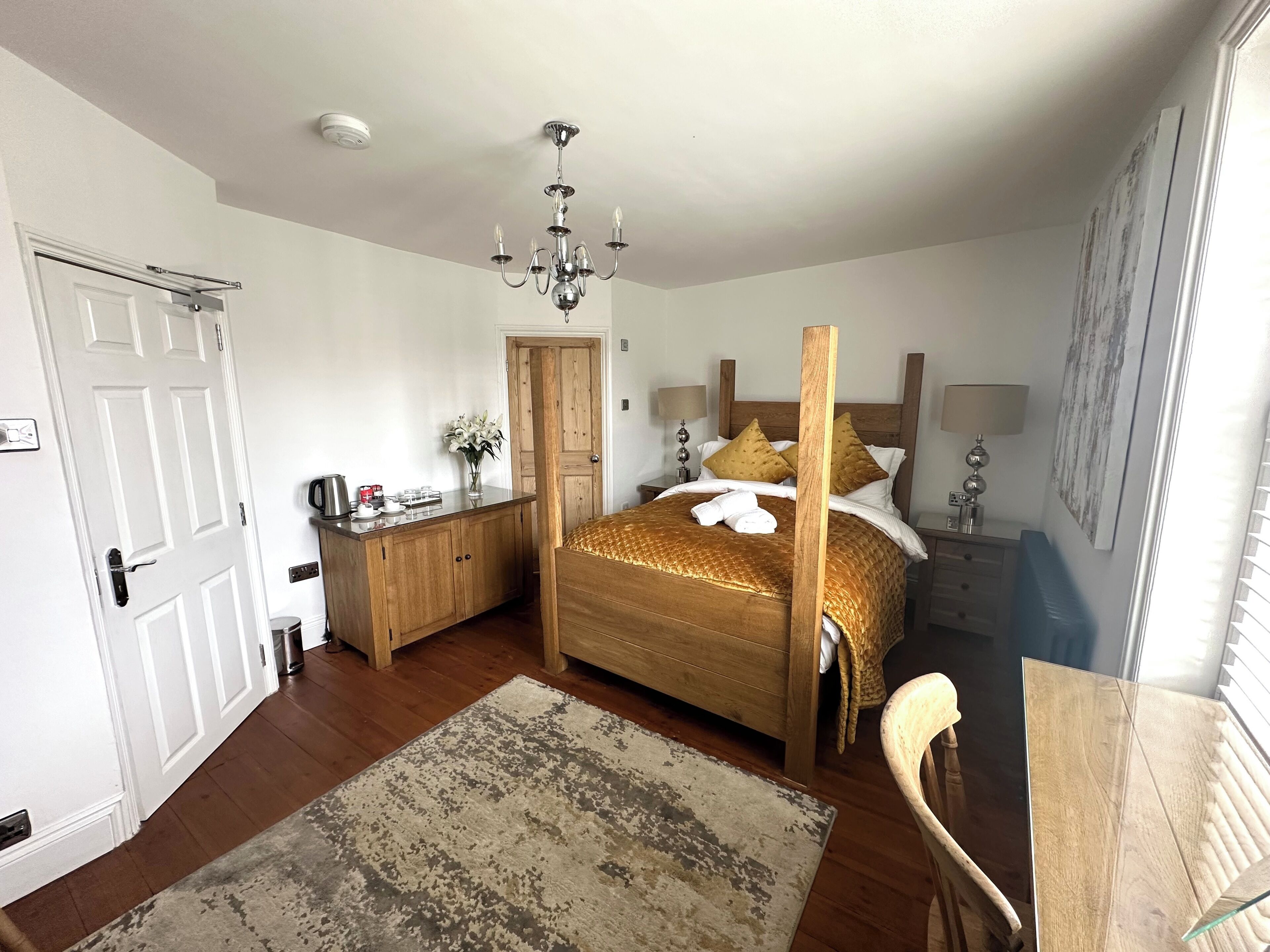 Une chambre avec un grand lit, des meubles en bois, un lustre et une vue sur l’extérieur.