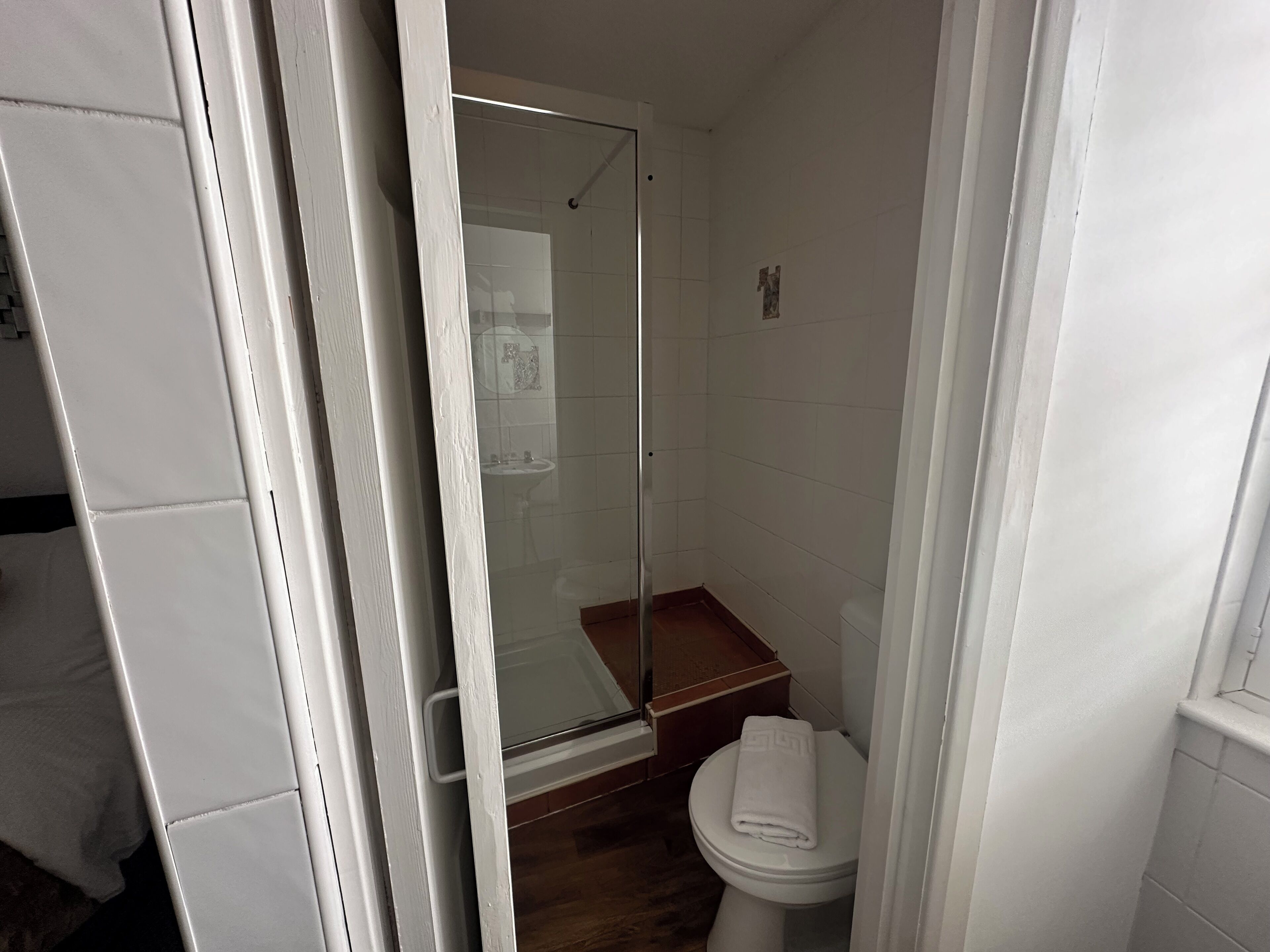 Ein Badezimmer mit Duschkabine aus Glas, einer weißen Toilette und einem Holzkabinet.