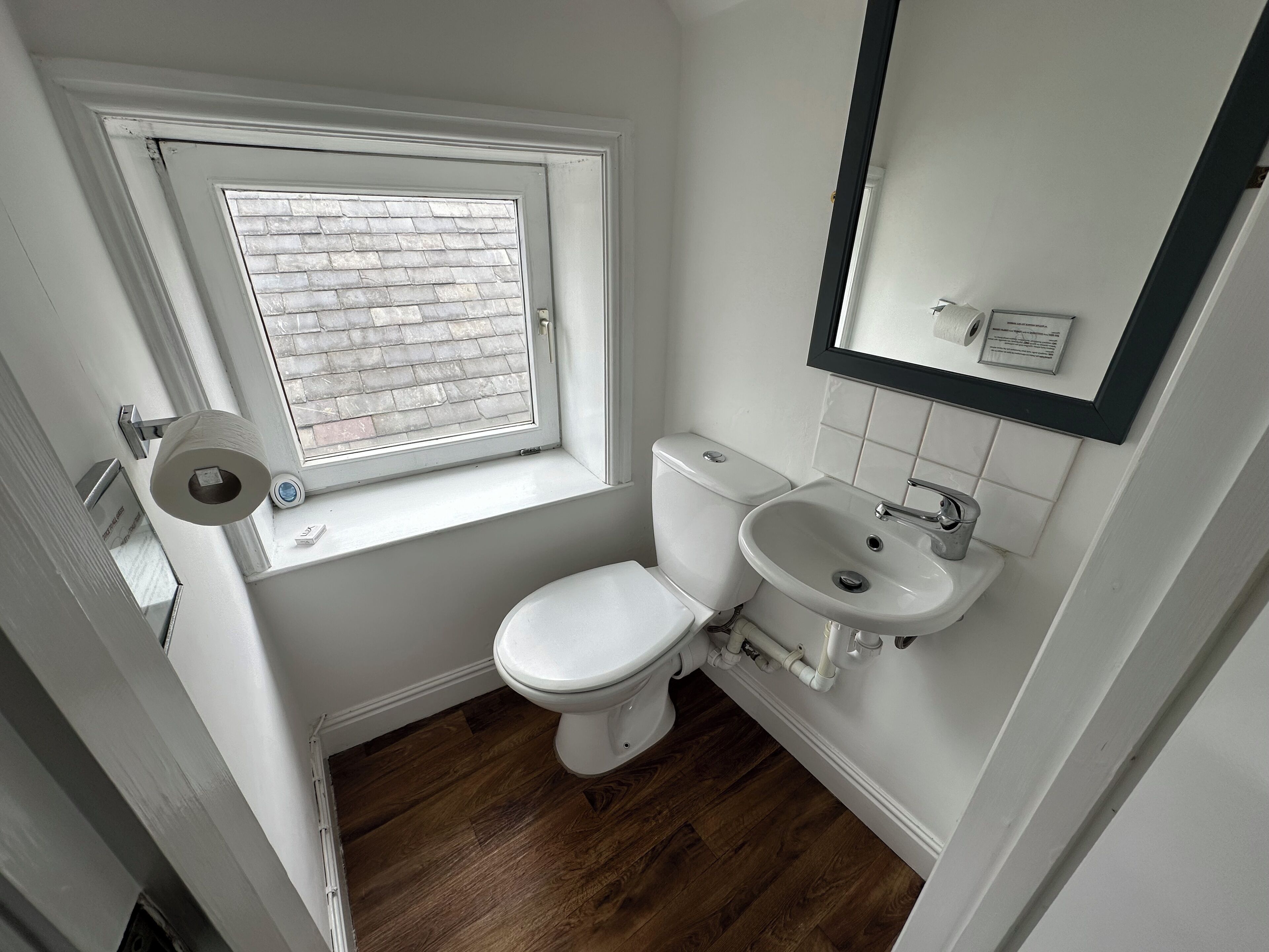 A small, clean bathroom with a toilet, sink, and window.