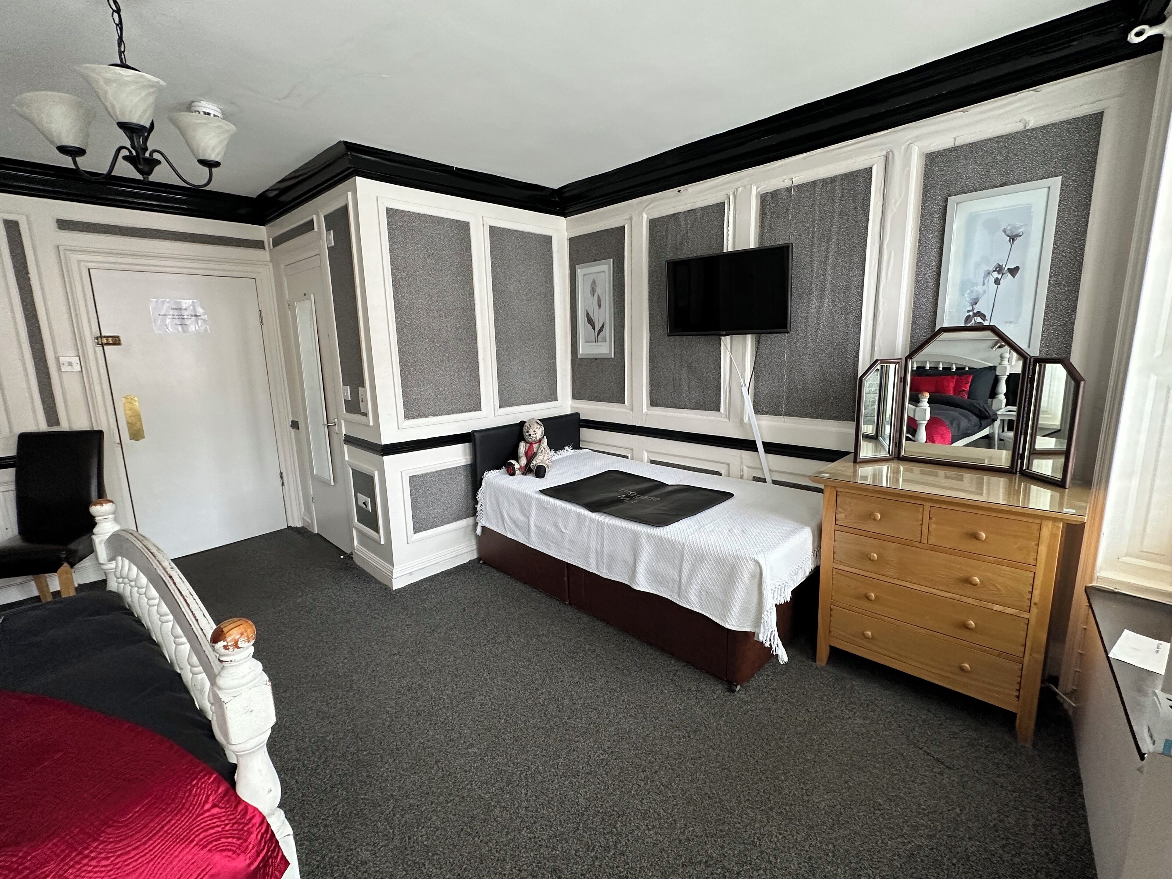 A bedroom with a bed, dresser, and a TV mounted on the wall.
