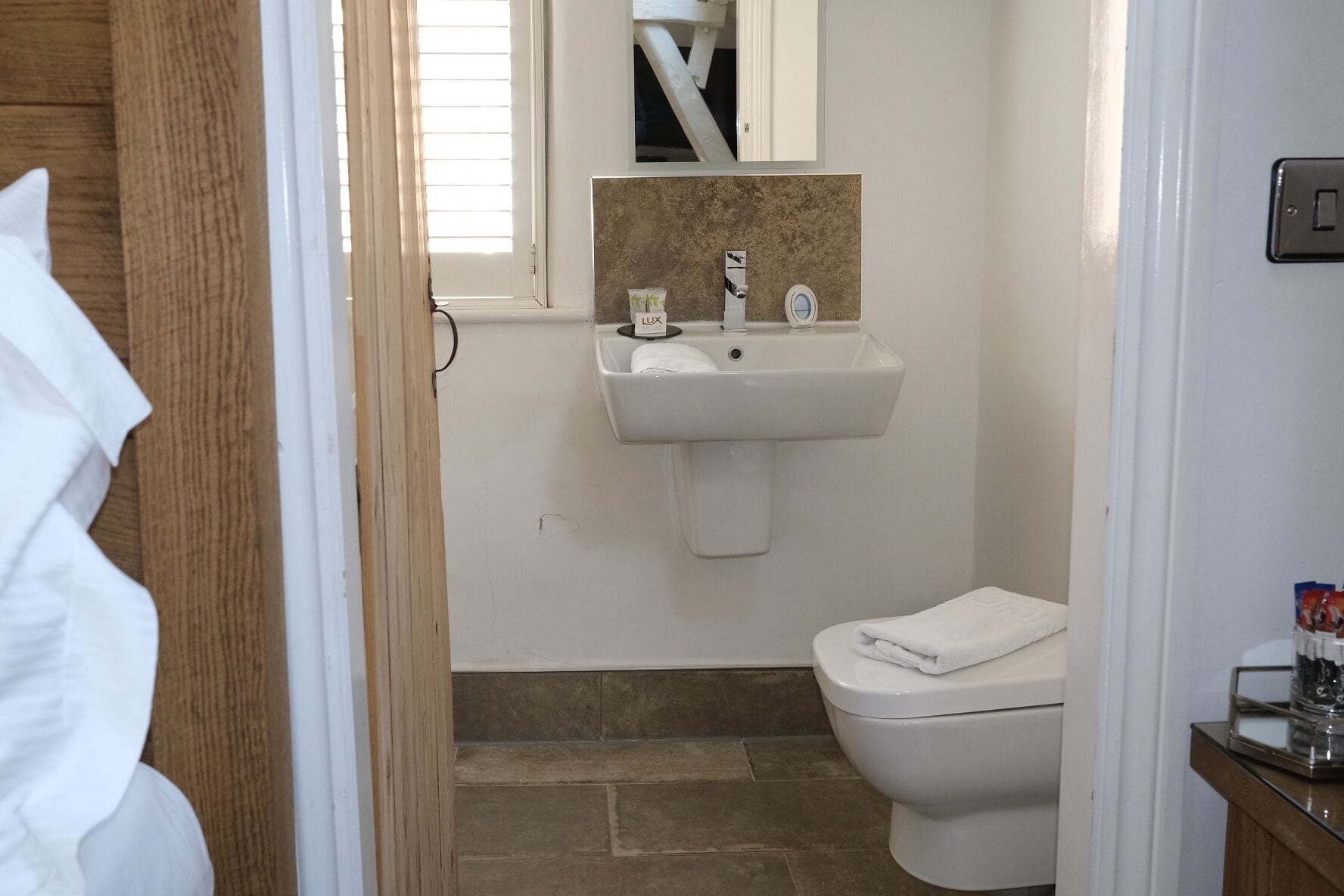 Une salle de bain avec un lavabo blanc, un miroir et des toilettes.