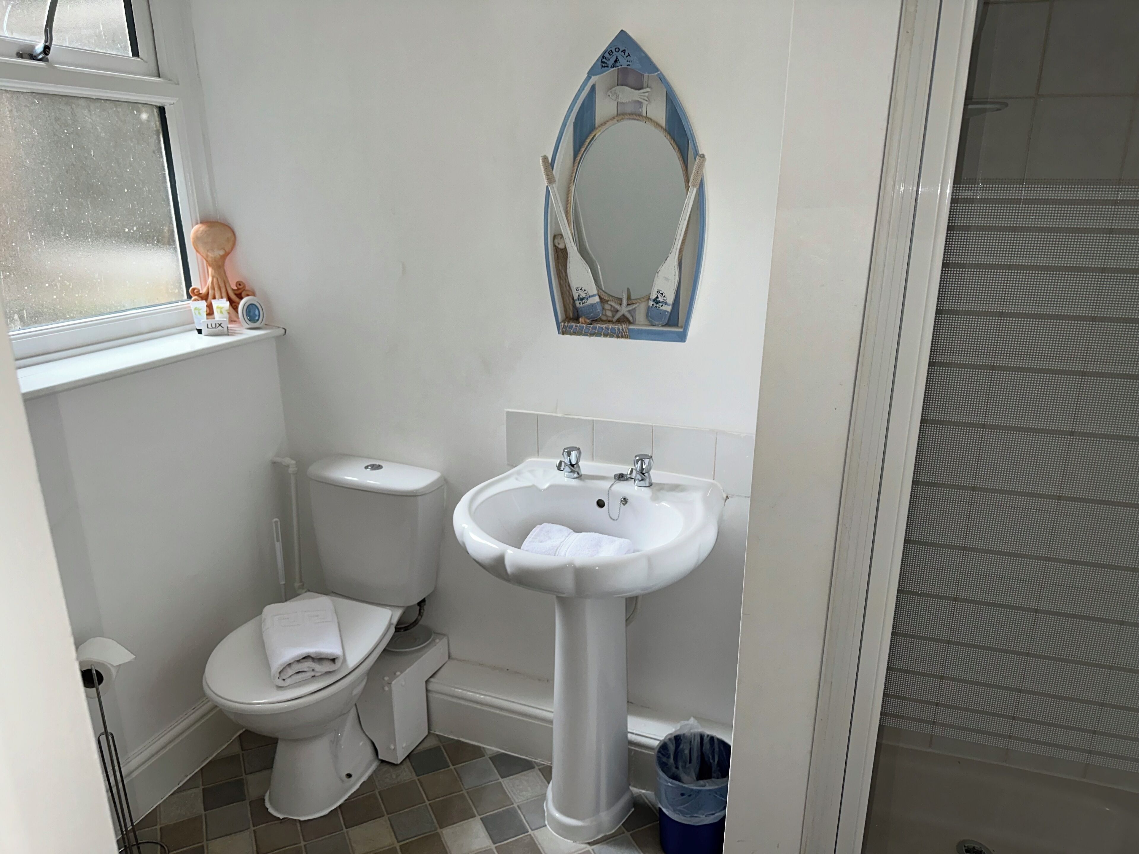 A bathroom with a toilet, sink, and a decorative mirror.