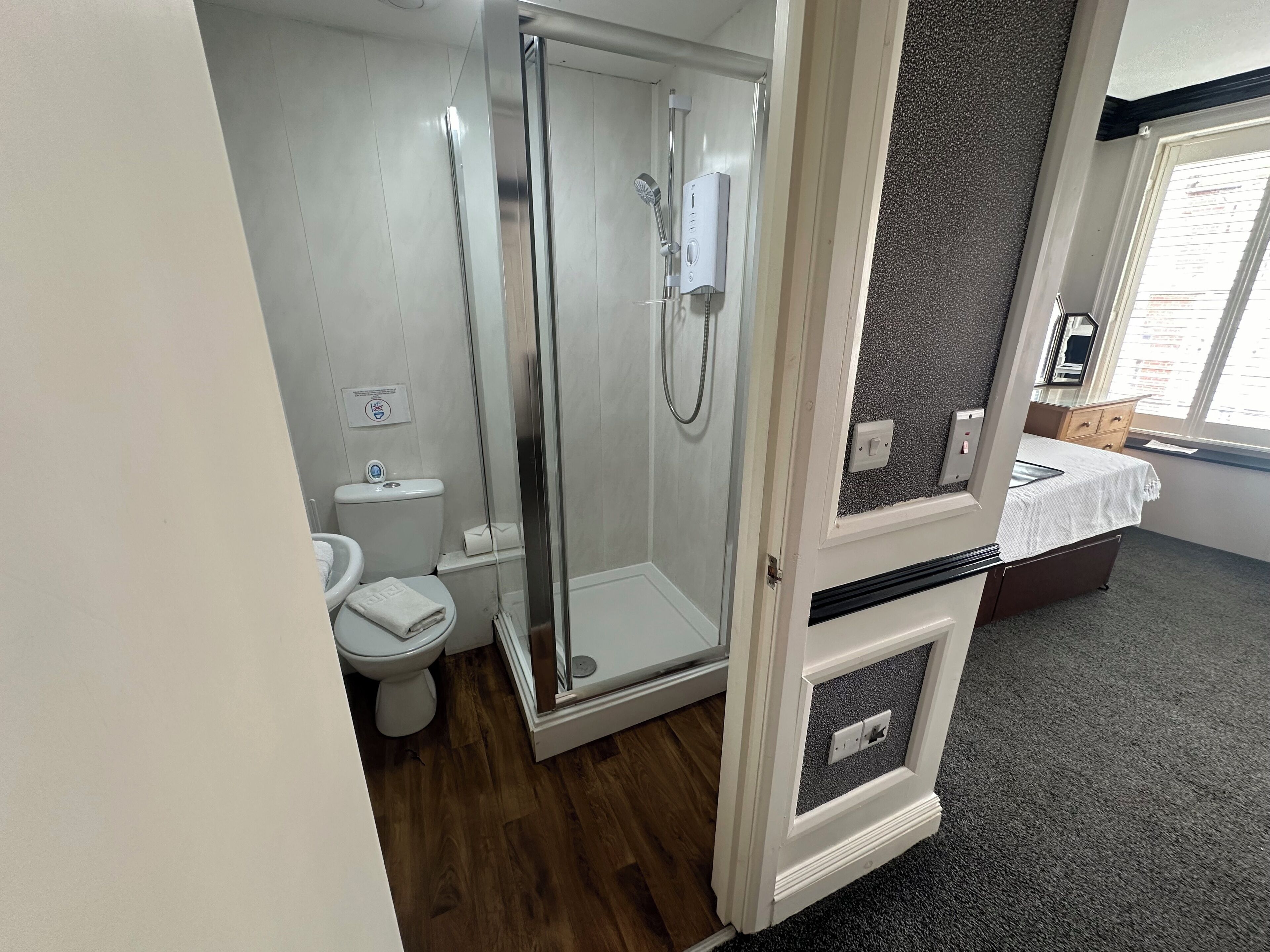 A modern bathroom with a glass-enclosed shower, a toilet, and a vanity with a mirror.