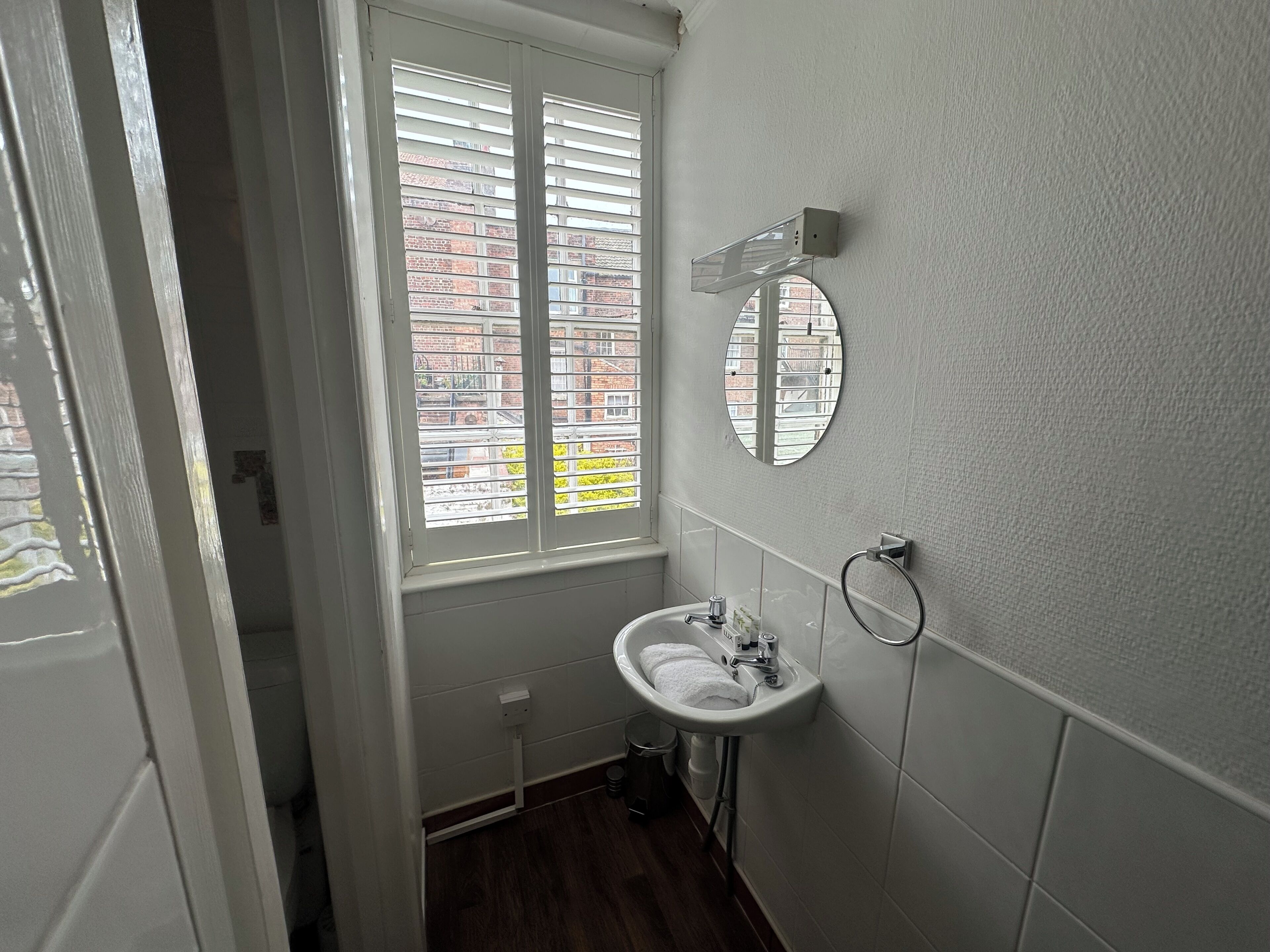 A bathroom with a window, a sink, and a mirror.