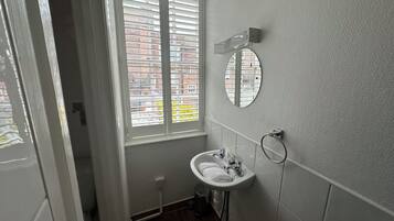 A bathroom with a window, a sink, and a mirror.