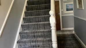 A staircase with a plaid carpet and white balusters. - Beechwood House (St Ives)
