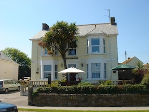 A two-story building with a sign 'Beechwood' on the front. There is a stone wall in front of the building, and a car is parked on the street. - Beechwood House (St Ives)
