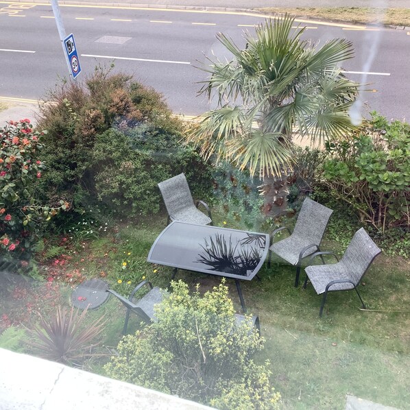 A patio with a table and four chairs, surrounded by various plants and flowers. - Beechwood House (St Ives)
