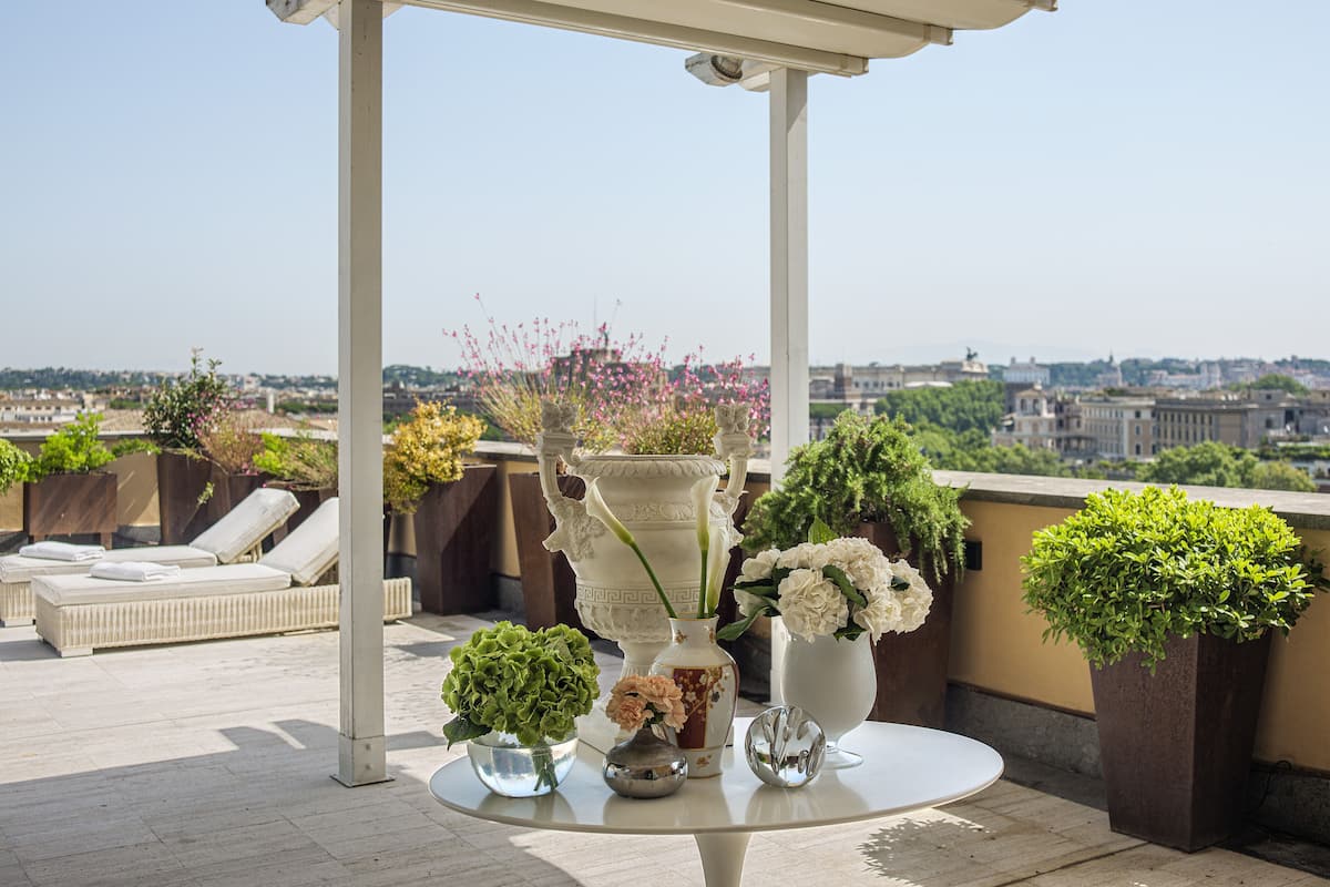 Una terrazza sul tetto con un tavolo rotondo, poltrone relax e piante in vaso.