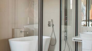 Un baño moderno con una bañera independiente, una zona de ducha con mampara de vidrio y un lavabo blanco.