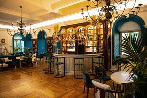 Zona de bar con suelo de madera, taburetes y una barra con botellas.