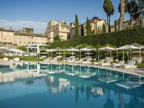 A pool area with lounge chairs and umbrellas, surrounded by buildings and trees. - Villa Agrippina Gran Meliá - The Leading Hotels of the World (Rome)