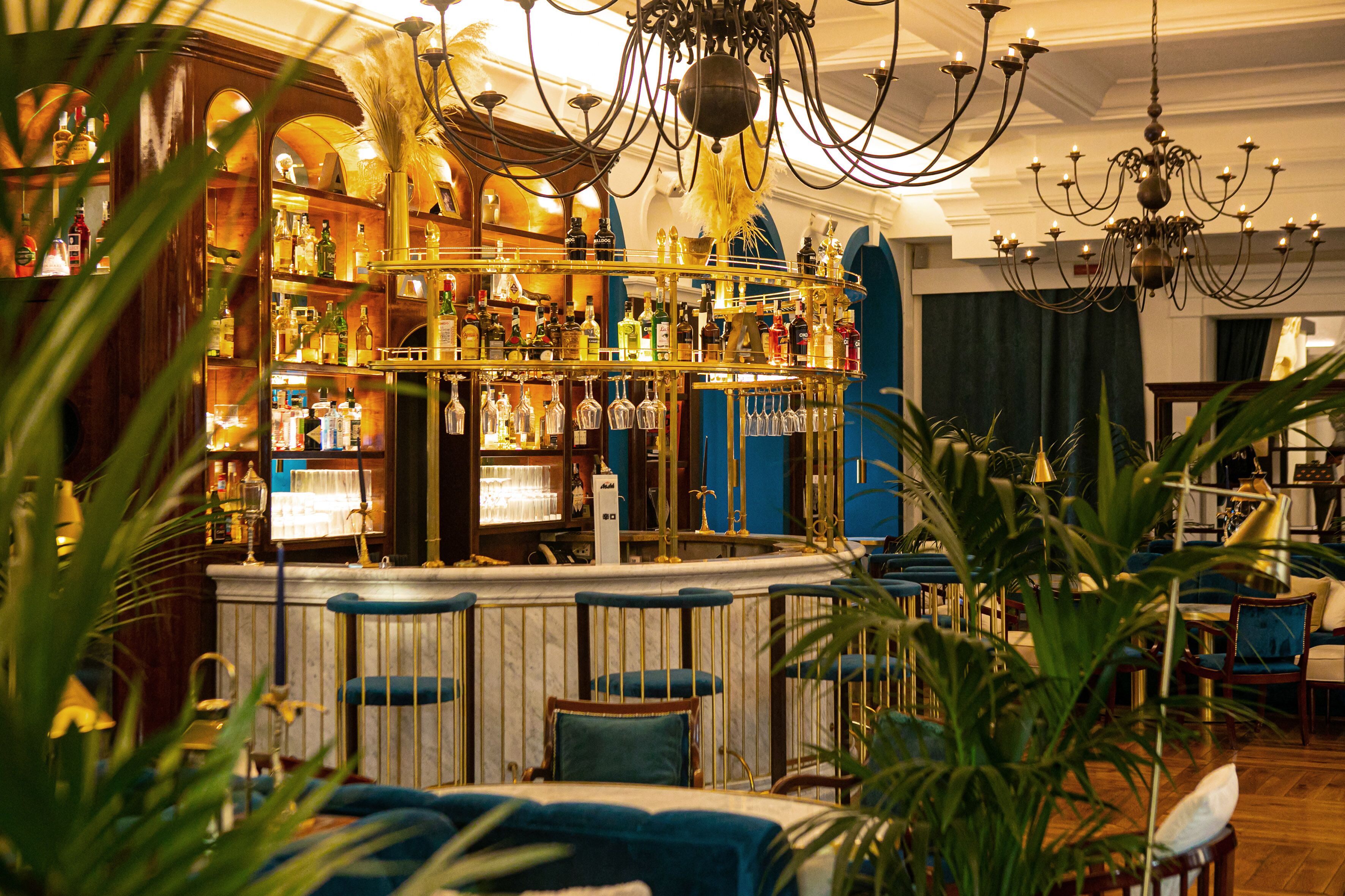 A bar area with a variety of liquor bottles, a bar counter, and seating with blue cushions.