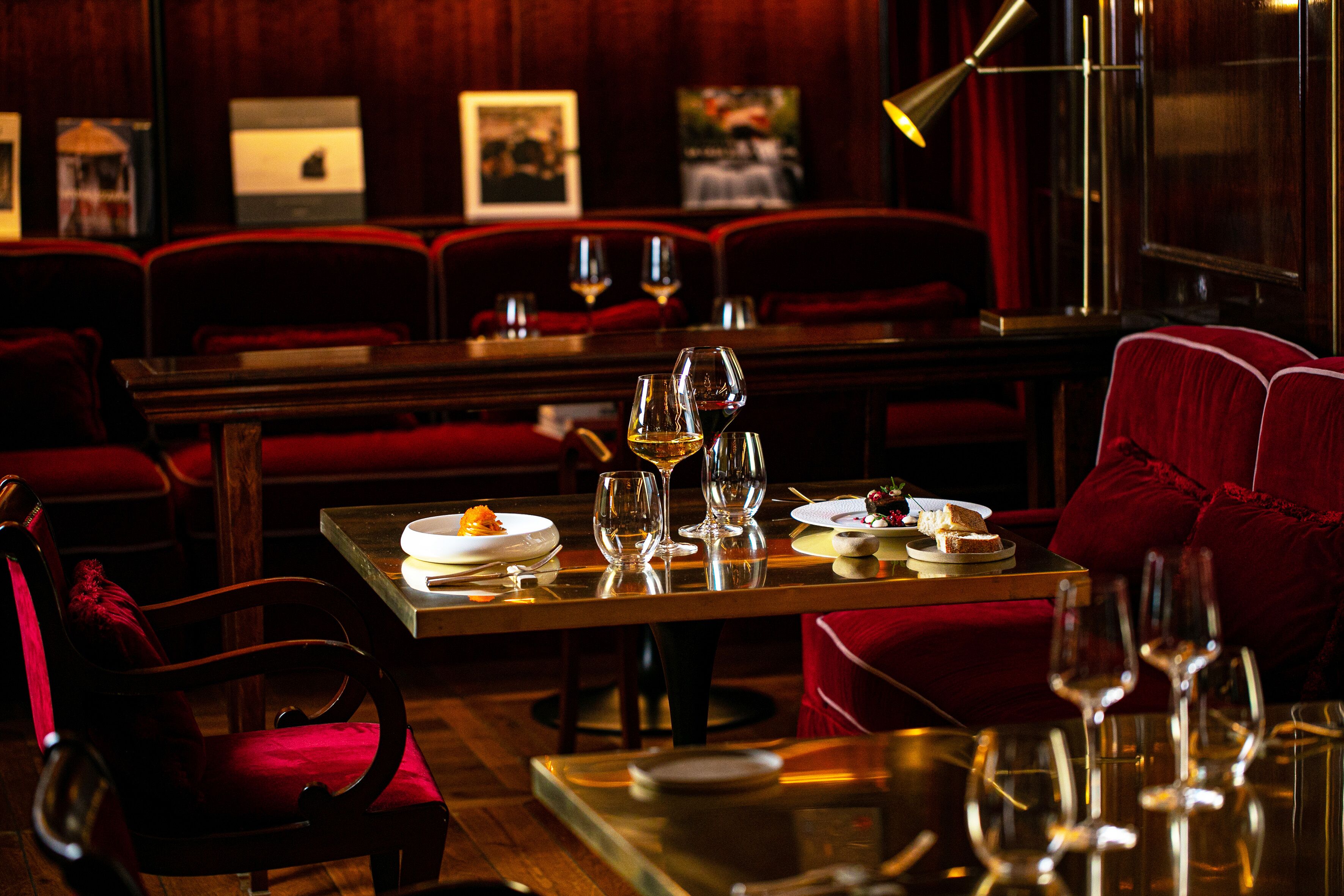 A restaurant with wooden furniture, red upholstery, and a table set with plates, glasses, and a candle.