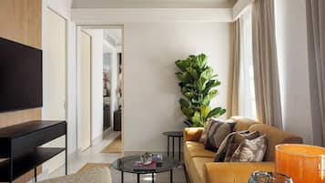 A modern living room with a flat-screen TV, a sofa, a coffee table, and a large plant.