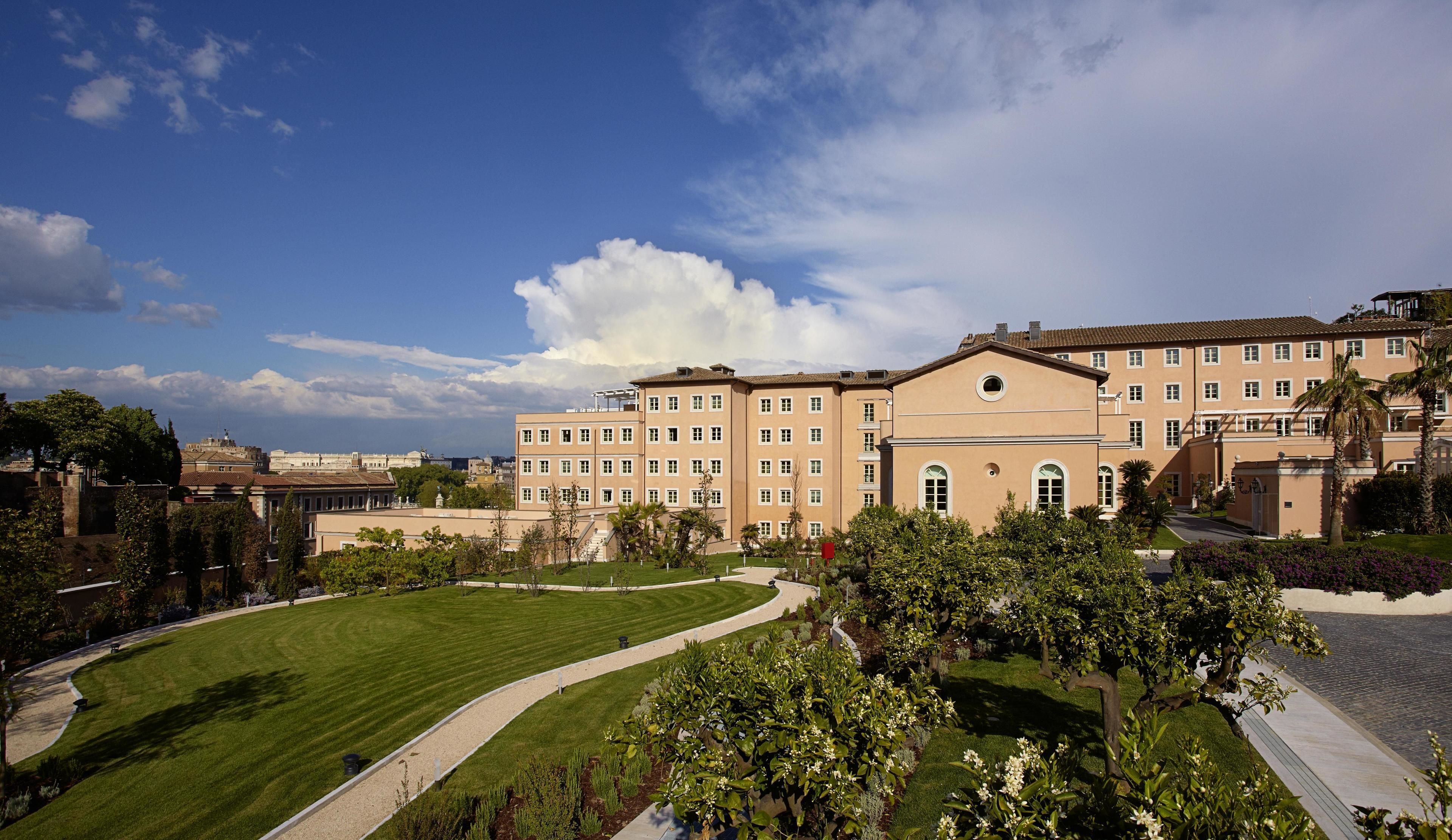 A large, multi-story building with a symmetrical facade, surrounded by well-maintained lawns and trees.