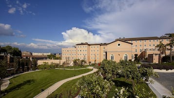 A large, multi-story building with a symmetrical facade, surrounded by well-maintained lawns and trees.