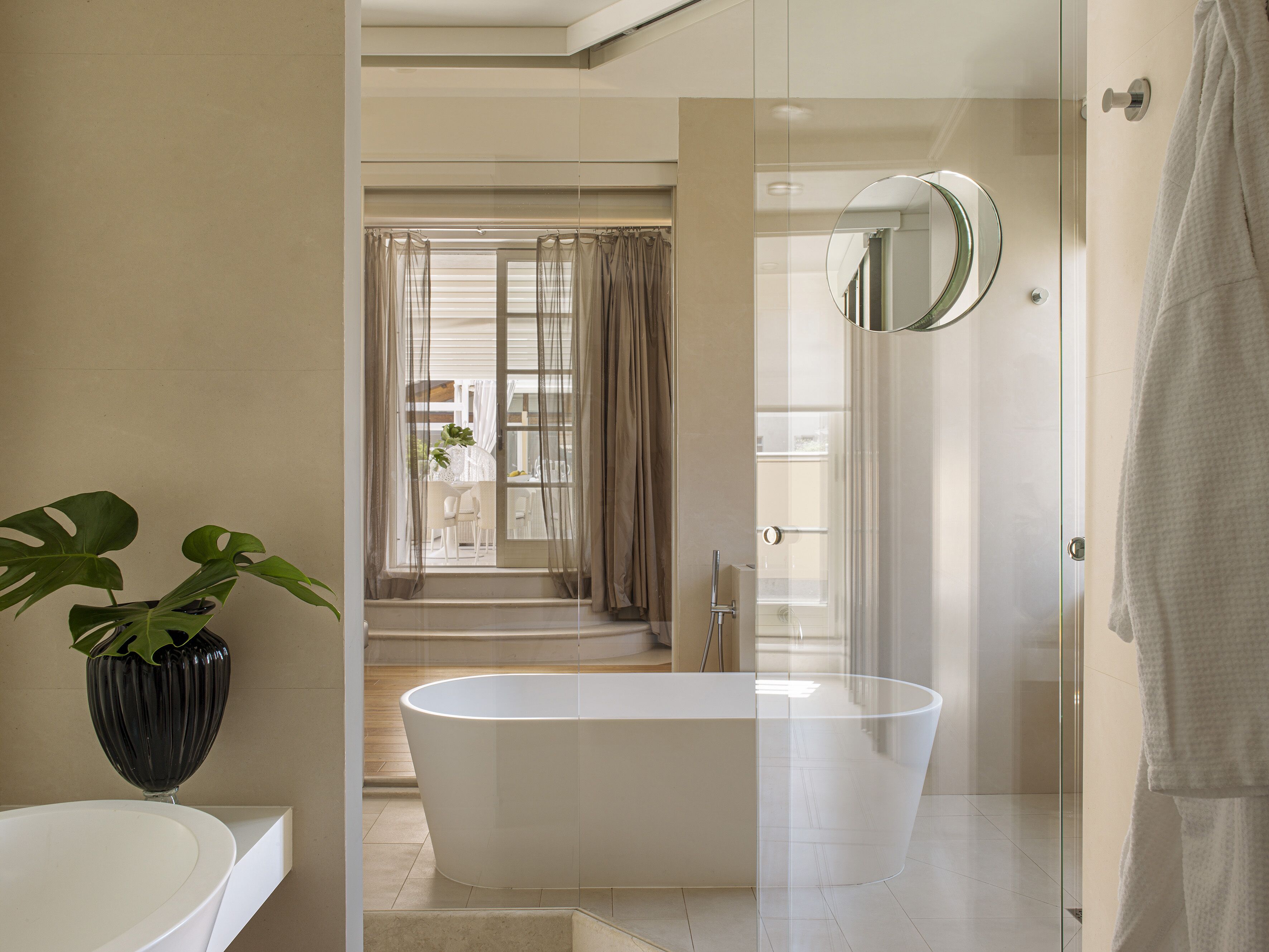 A modern bathroom with a freestanding bathtub, a glass shower enclosure, and a large mirror.